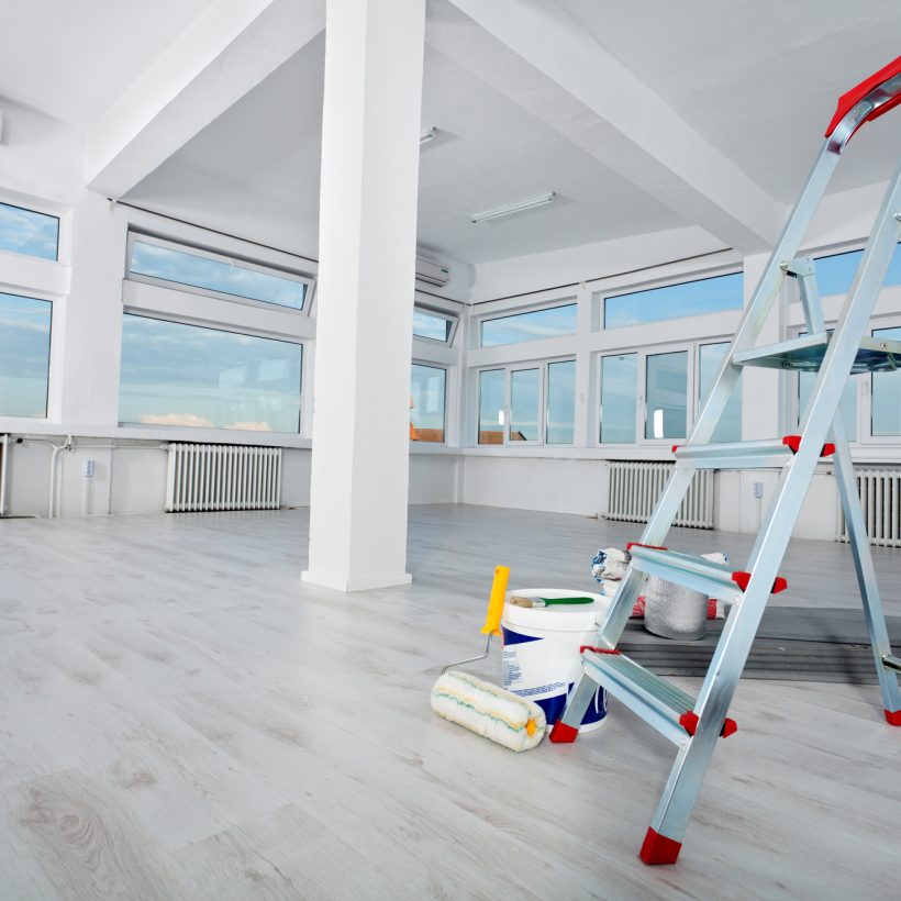 Newly renovated generic empty office space with leftover materials and ladder in foreground